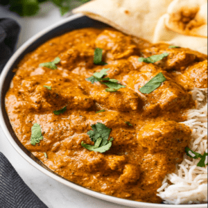 bowl of Indian butter curry chicken over rice with naan bread
