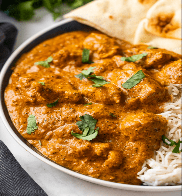 bowl of Indian butter curry chicken over rice with naan bread