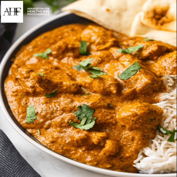 Butter chicken over white rice in bowl with naan bread.
