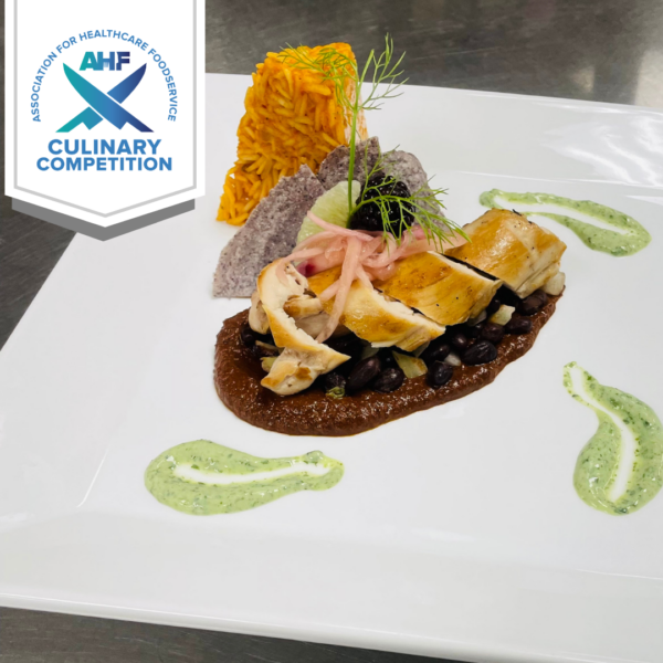 square plate with a tower of Spanish rice next to a chicken thigh atop mole sauce.